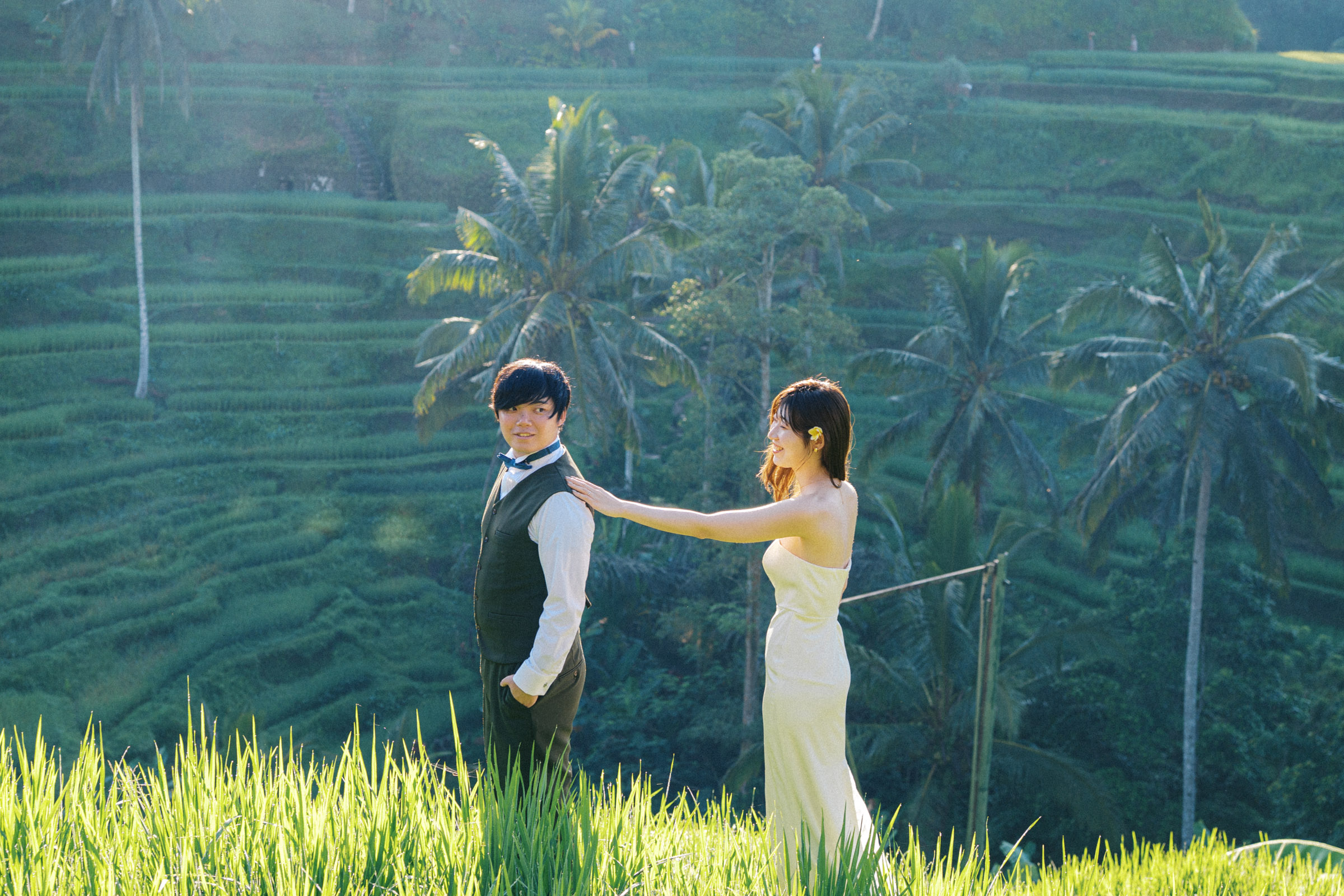 Mika resting her hand on Tatsu’s shoulder among the green rice terraces